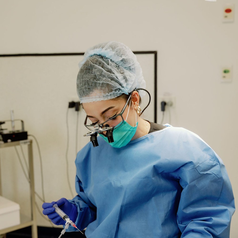 A doctor at 3D Hair Transplant, gowned and using surgical loupes, working with precision during an FUE procedure, Gold Coast